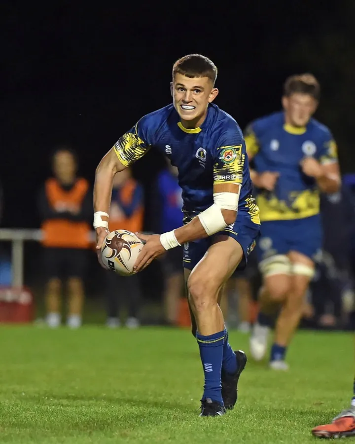 A Brunel back in the navy and gold home shirt kicks from hand under floodlights.